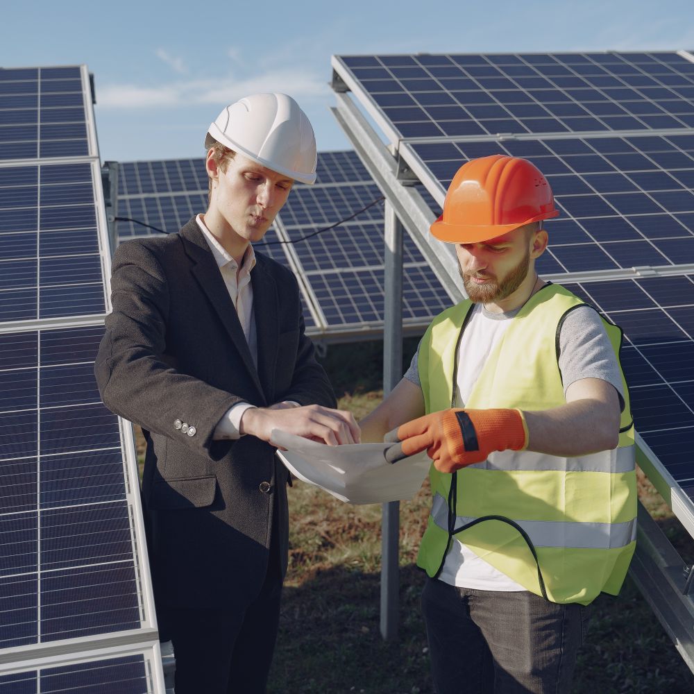 Güneş panellerinin yanında teknik dokümanları inceleyen uzmanlar